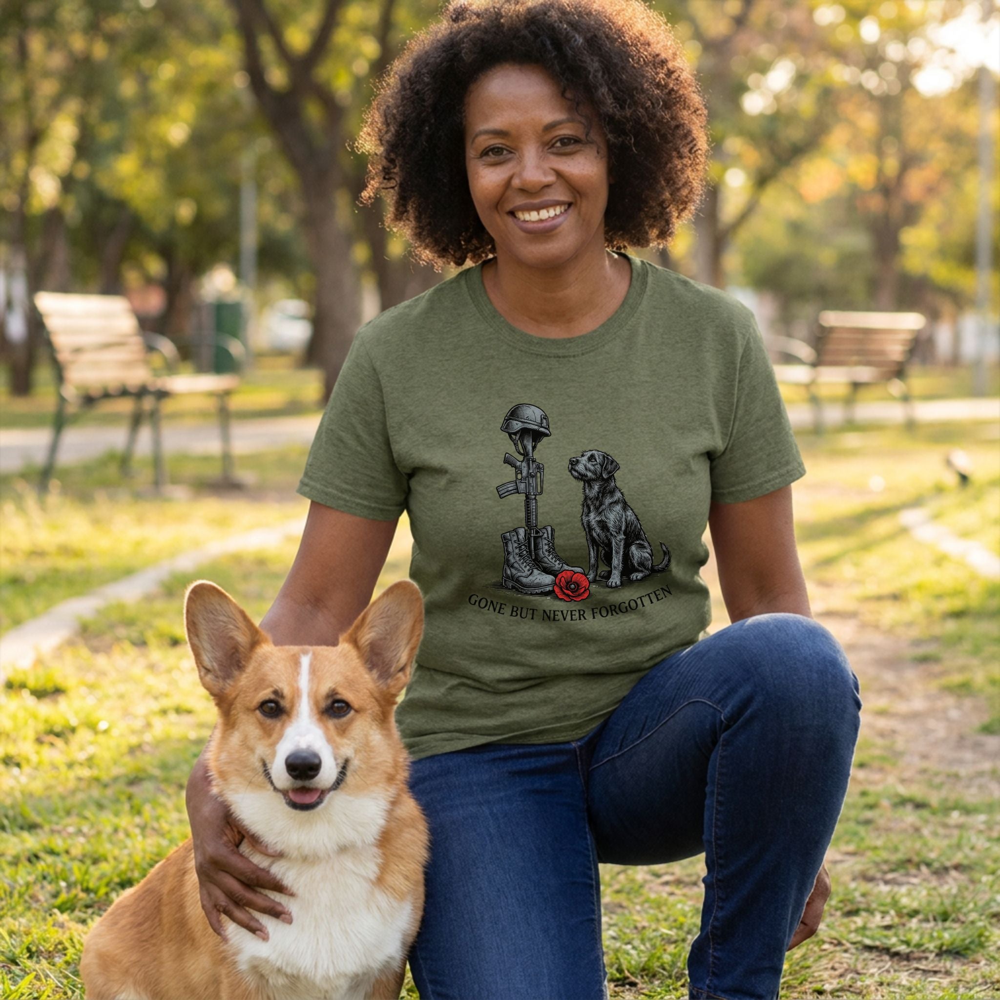 Woman in an olive green "Gone Not Forgotten" tee with a military memorial and black dog design, petting a corgi.