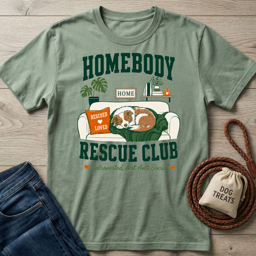 Sage green crewneck t-shirt featuring a graphic of a sleeping rescue dog on a couch with Homebody Rescue Club text.