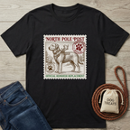 Black t-shirt with a vintage "North Pole Post" stamp design featuring a Labrador retriever in a harness with antlers.