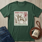 Forest green t-shirt with a vintage "North Pole Post" stamp design featuring a Labrador retriever in a harness with antlers.