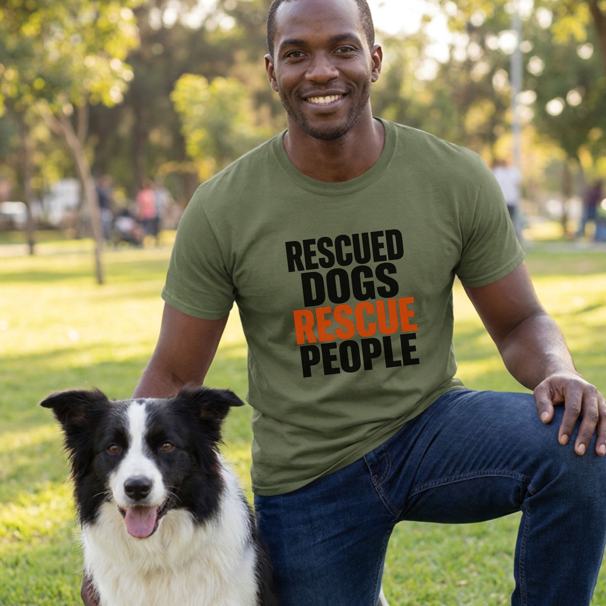Man in olive green "Rescued Dogs Rescue People" t-shirt kneeling beside a black and white border collie.