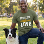Man in an olive green "Rescue Dog Unconditional Love" t-shirt kneeling beside a black and white border collie.
