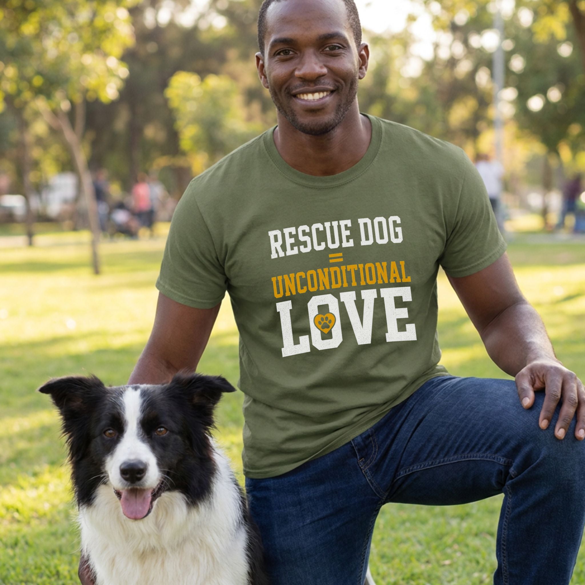 Man in an olive green "Rescue Dog Unconditional Love" t-shirt kneeling beside a black and white border collie.