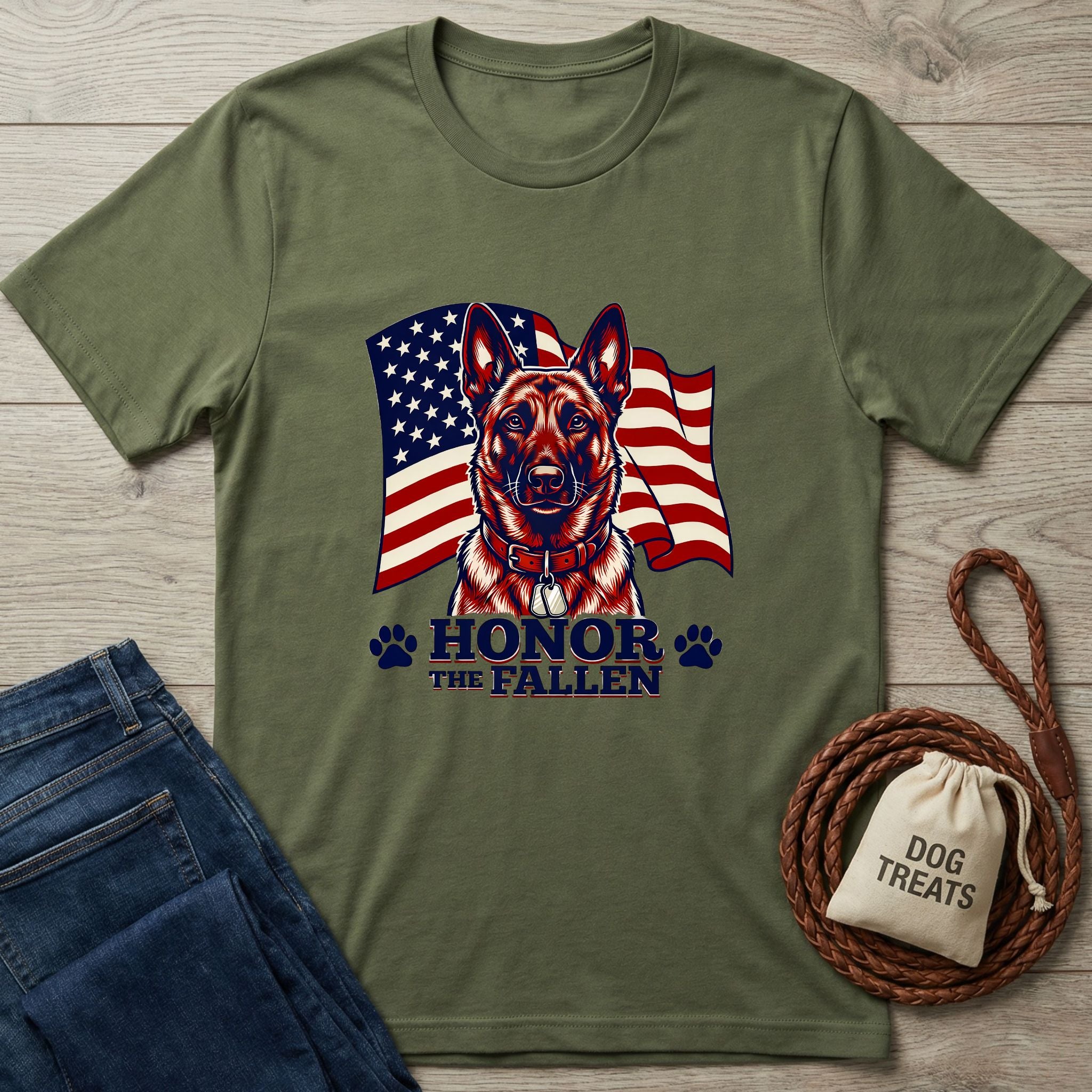 Olive green Honor The Fallen T-shirt with a German Shepherd and American flag design, next to jeans and dog treats.