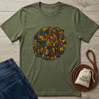 Green t-shirt with colorful tiger design on a wooden surface with jeans and a dog treat bag.