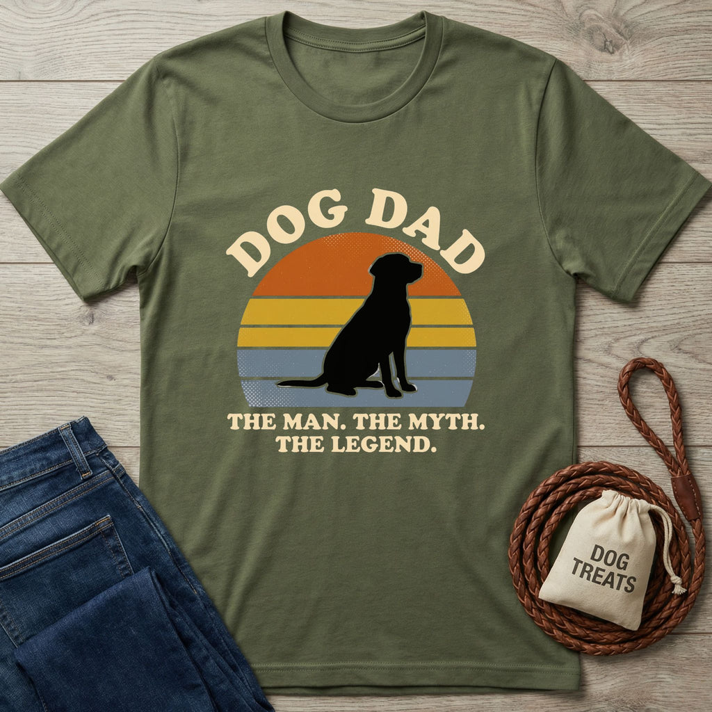 Olive green "Dog Dad" t-shirt with a black dog silhouette, sunset graphic, jeans, and dog treats bag.