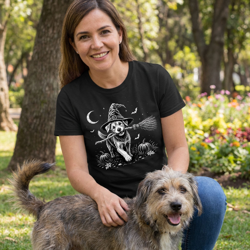 Woman wearing a black T-shirt featuring a white graphic of a dog in a witch hat holding a broomstick in a pumpkin patch.