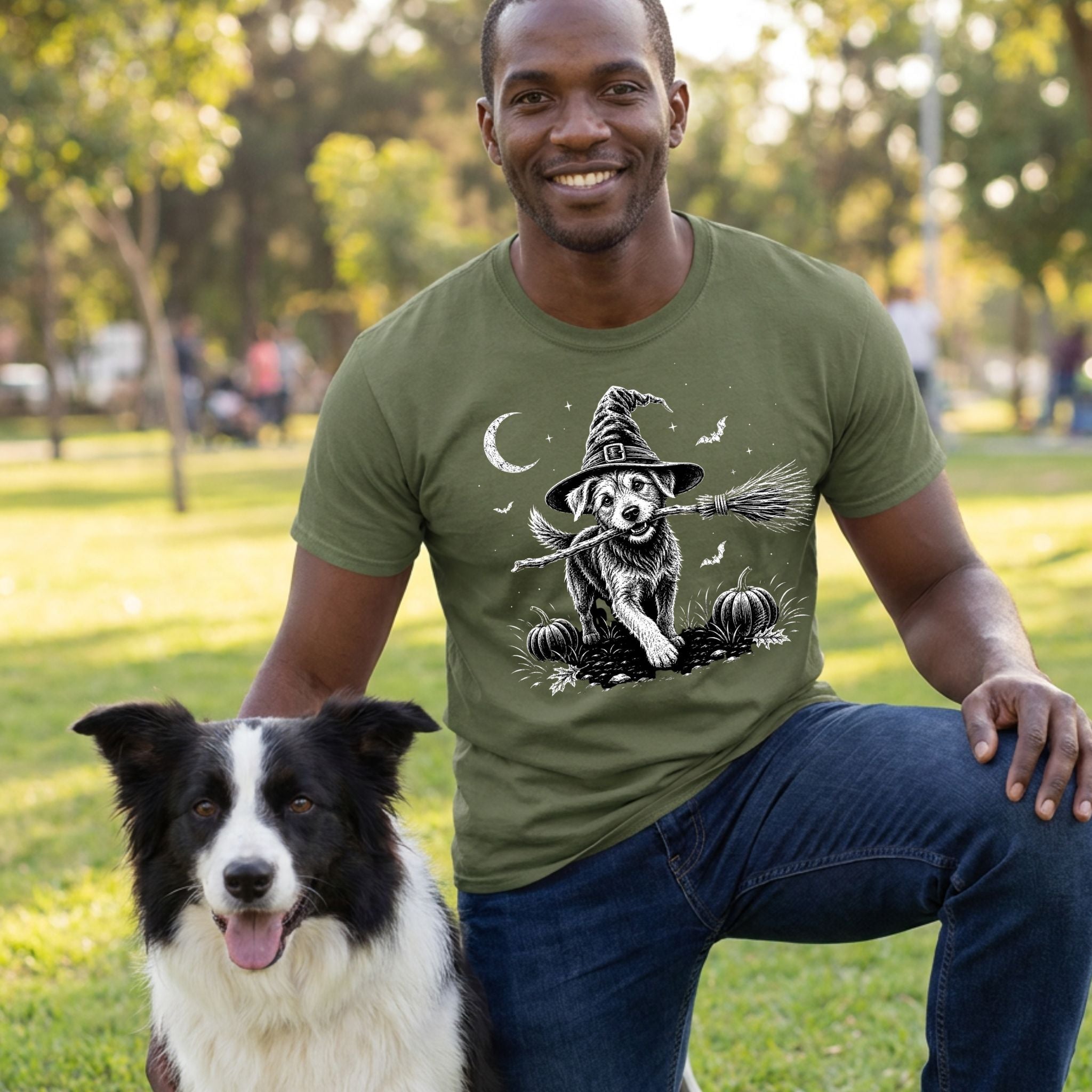 Man wearing an olive green crewneck t-shirt featuring a graphic of a dog in a witch hat holding a broomstick.