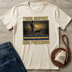 Cream "Their Service Our Freedom" t-shirt with soldier and dog graphic, next to jeans and dog treats bag.
