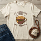 Cream Gildan Softstyle t-shirt with "Not a Morning Person, Only a Morning Dog" text and a sleeping dog in a mug graphic.