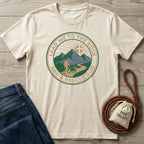 Cream cotton t-shirt with "Lead Me To The Rock And A Rescue Dog" graphic featuring mountains, sun, hiker, and dog.
