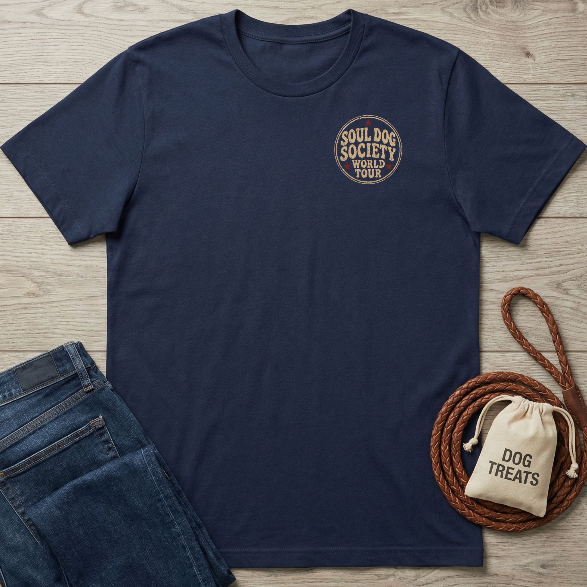 Navy blue Gildan Softstyle® 64000 t-shirt with "Soul Dog Society World Tour" logo on chest, beside jeans and dog treats.