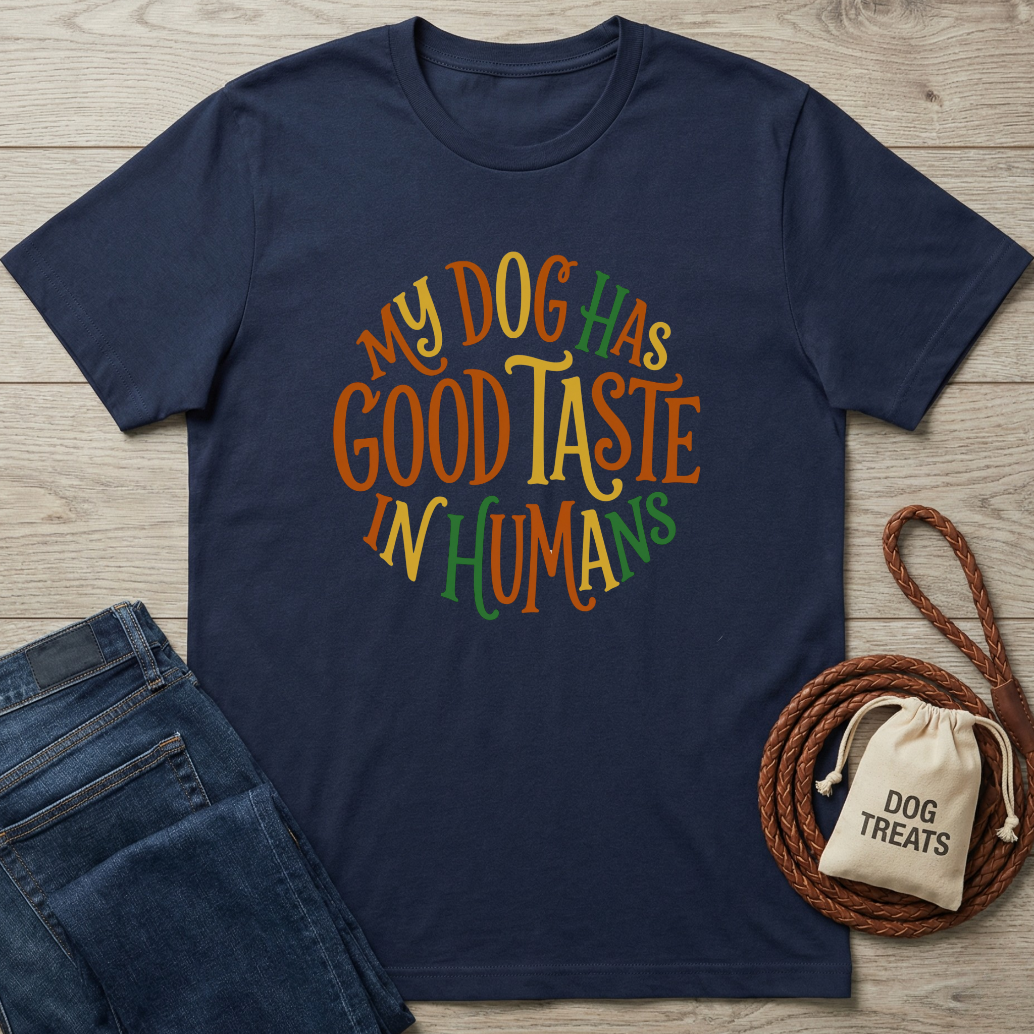 Navy blue cotton t-shirt with "My Dog Has Good Taste In Humans" in colorful, circular text.