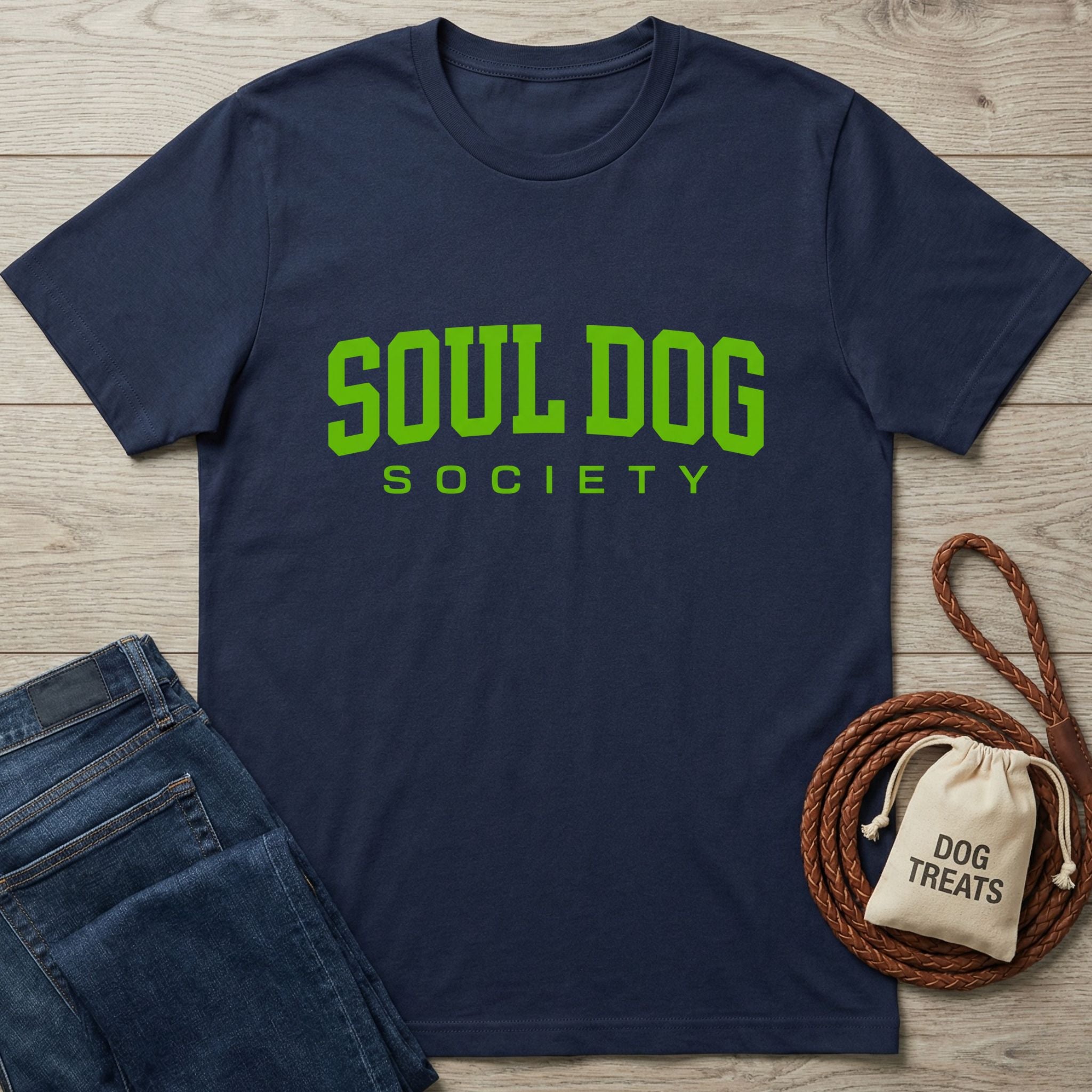 Navy blue Soul Dog Society T-shirt with bright green text, next to jeans and a dog treat bag.