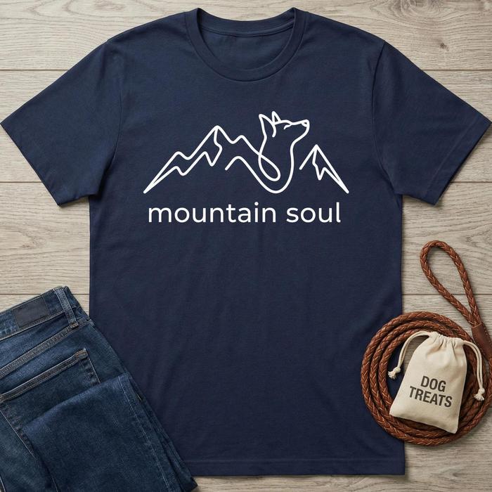 Navy cotton "Mountain Soul" t-shirt with white mountain and dog line art design, next to jeans and dog treats.