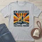 Grey crewneck t-shirt featuring a retro mountain, sunrise, and dog-and-owner graphic with New Adventures Faithful Friend text.