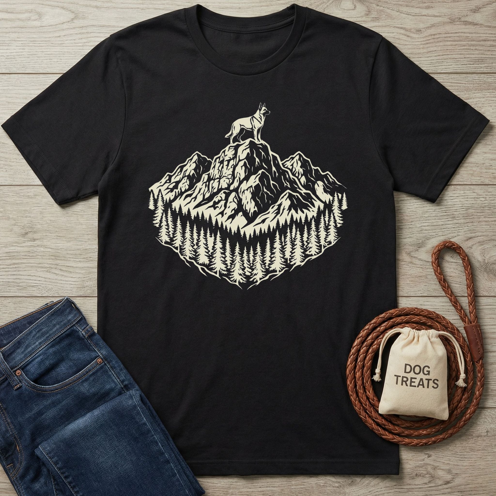 Black cotton t-shirt with a cream graphic of a dog on a mountain peak surrounded by pine trees.