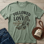 Sage green "Followed By Love Everywhere I Go" t-shirt with a boot print and paw prints.