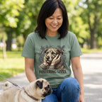 Woman in a green "Fostering Lives" tee with a dog graphic, petting a pug outdoors.
