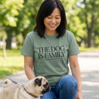 Woman in an olive green "The Dog Is Family" t-shirt with a pug on a leash.