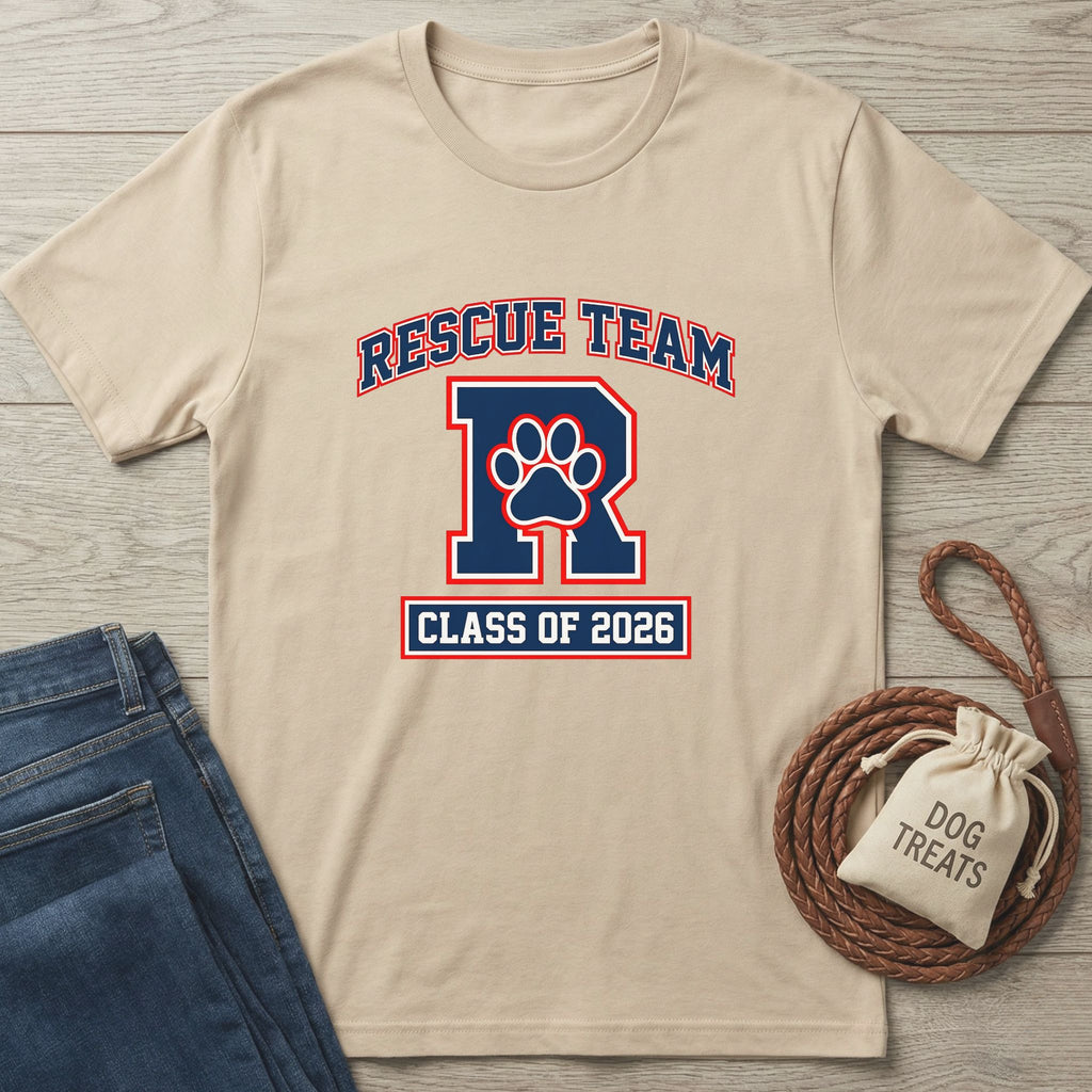 Tan "Rescue Team" t-shirt with a paw print "R" and "Class of 2026" design, next to jeans and dog treats.