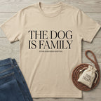 Beige Gildan Softstyle® t-shirt with "THE DOG IS FAMILY" text, next to jeans and dog treats.