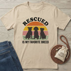 Beige Gildan Softstyle t-shirt with "RESCUED IS MY FAVORITE BREED" text and three dog silhouettes.