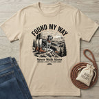 Found My Way T-shirt in sand with a graphic of a person and dog hiking, surrounded by jeans and dog treats.