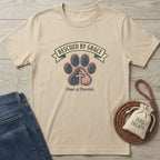 Paws & Prayers T-Shirt: Tan Gildan Softstyle tee with "Rescued by Grace" text, paw print, and cross design.