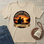 Golden Souls T-shirt: beige cotton tee with a graphic of a person and dog watching a sunset over a lake.