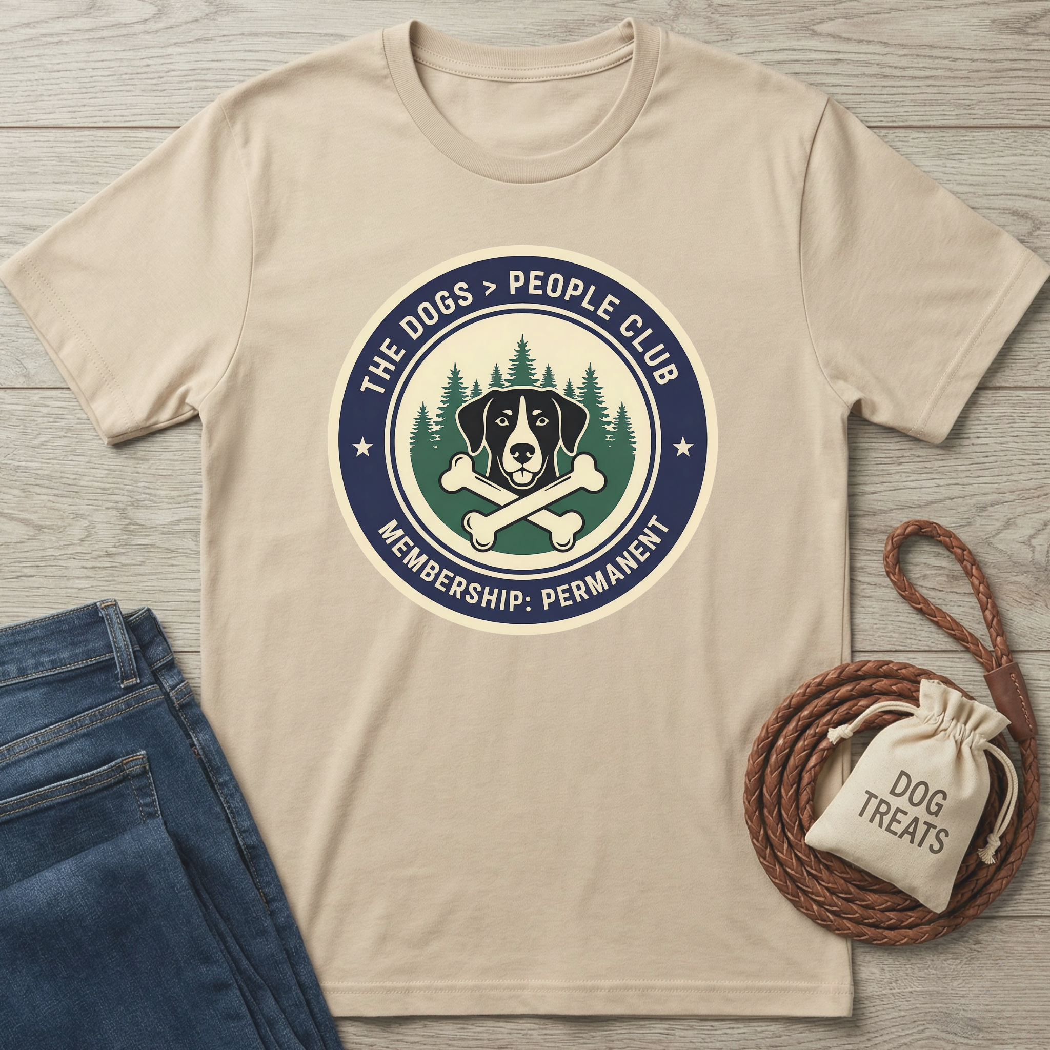 Beige cotton t-shirt with "The Dogs > People Club" logo featuring a dog, crossed bones, and pine trees.