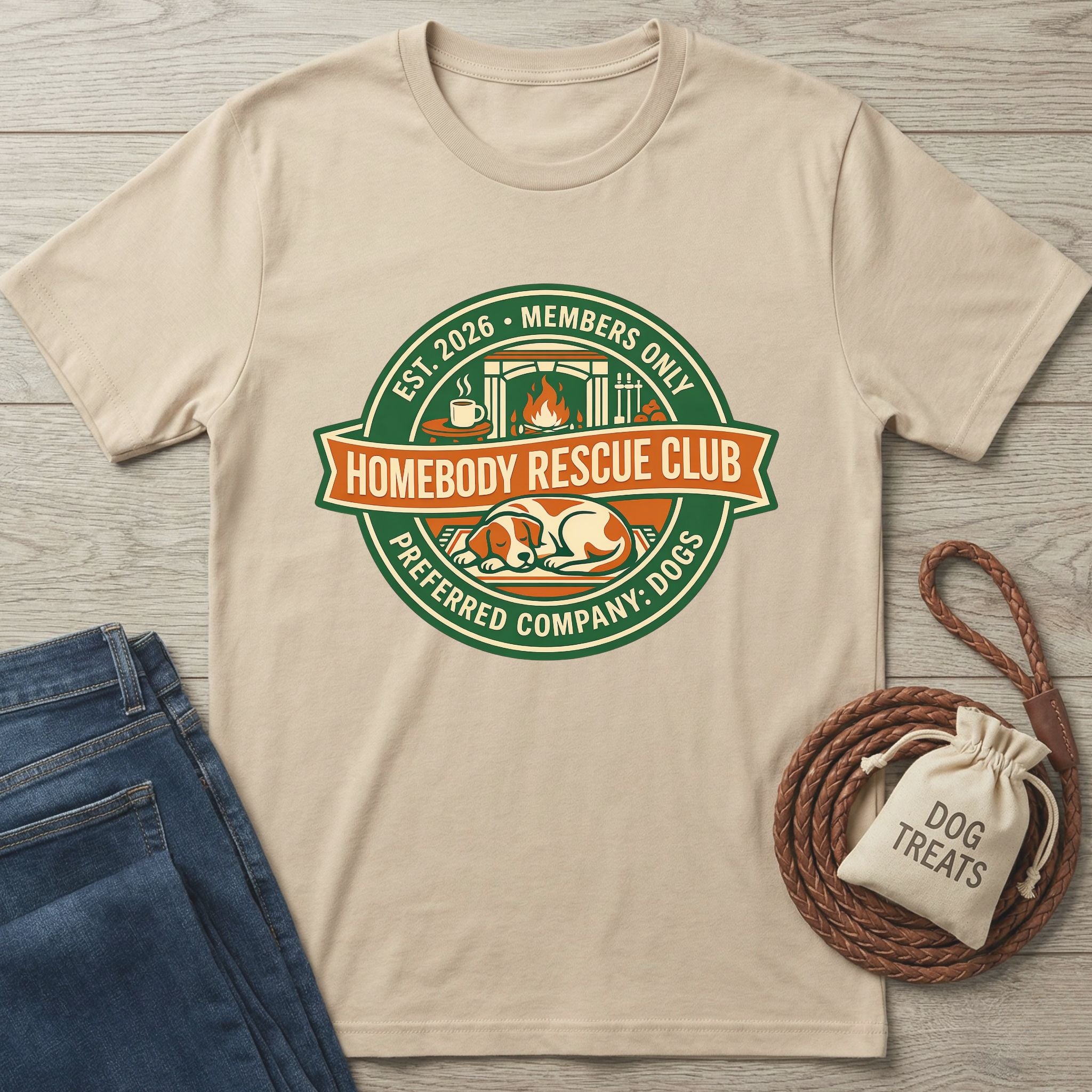 Beige Homebody Rescue Club T-shirt with a sleeping dog graphic, next to jeans and a "Dog Treats" bag.