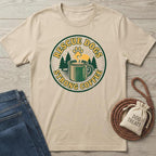 Beige cotton t-shirt with "Rescue Dogs Strong Coffee" graphic, green trees, yellow paw print, and coffee mug.