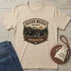 Beige "Silver Muzzle Society" t-shirt with a sleeping senior dog graphic, next to jeans and dog treats.