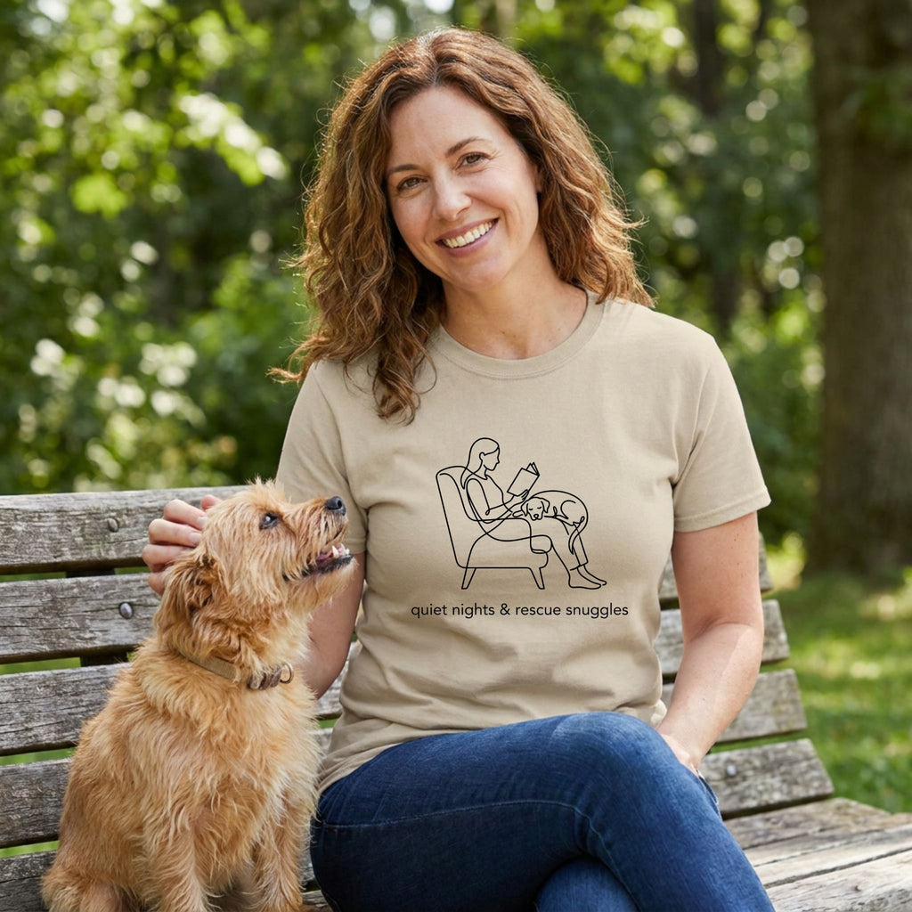 Woman in a tan "Quiet Nights & Rescue Snuggles" tee, petting a dog on a park bench.