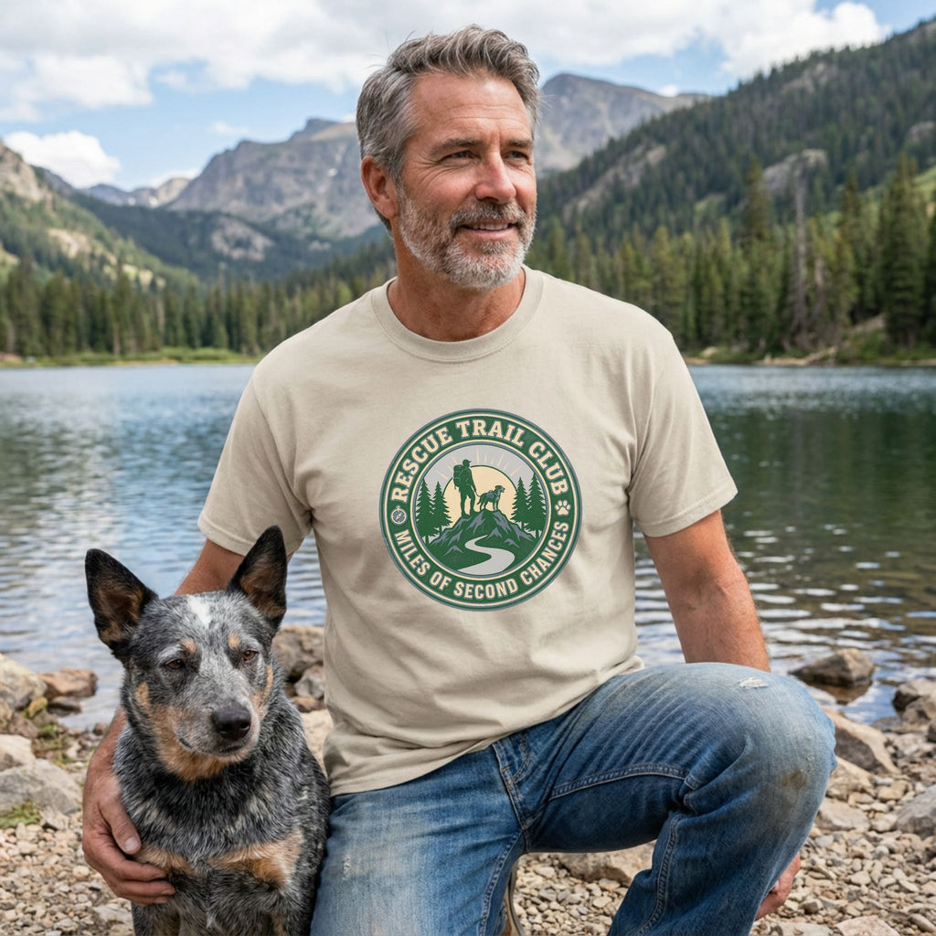 Man in a beige "Rescue Trail Club" tee with a dog, mountains, and lake in the background.