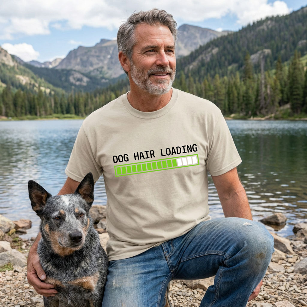 Man in a tan "Dog Hair Loading" t-shirt with a blue heeler dog by a lake.