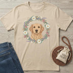 Beige t-shirt with a dog illustration and floral wreath, paired with jeans and a dog treat bag on a wooden surface.