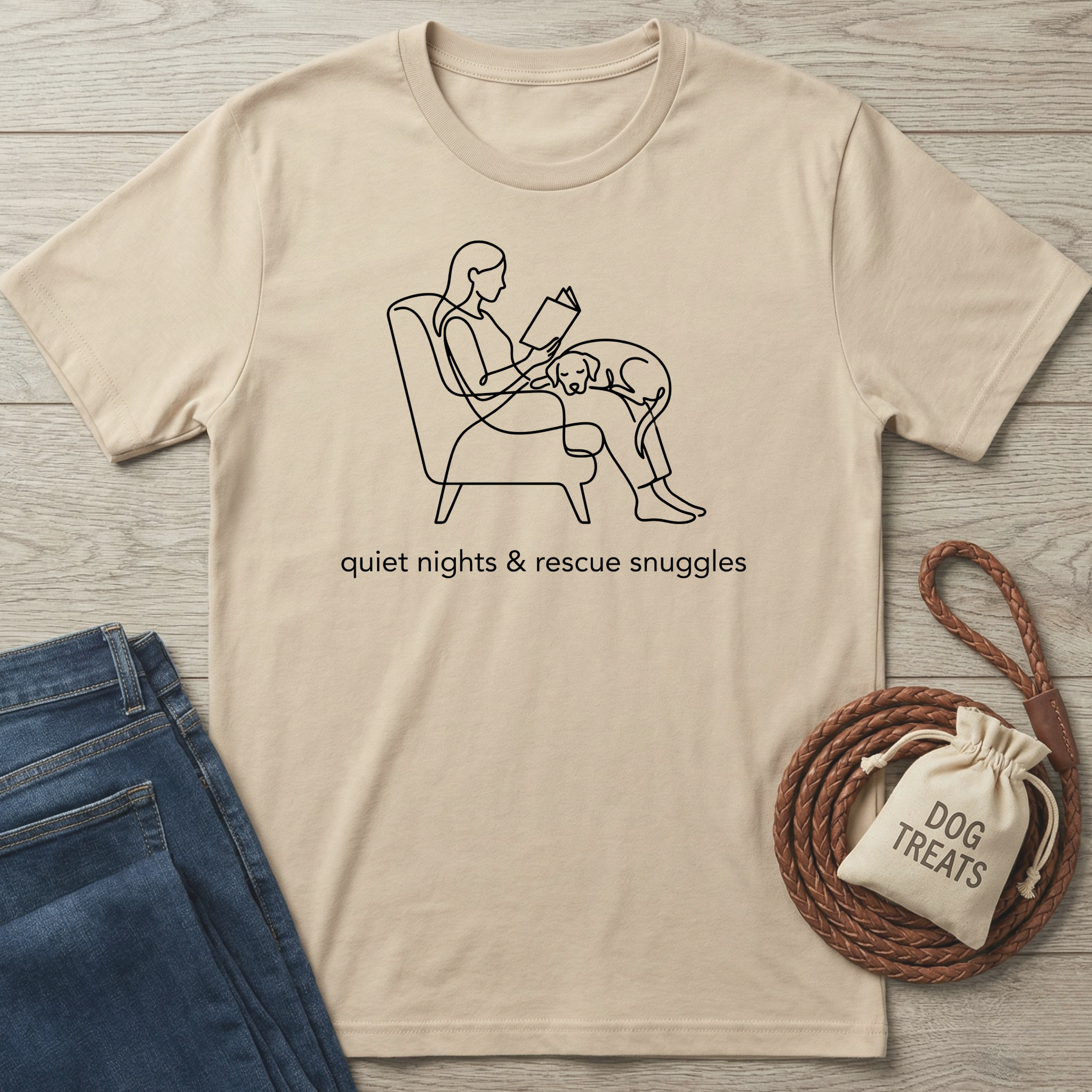 Beige cotton t-shirt with black line art of a person reading with a dog, "quiet nights & rescue snuggles" text.