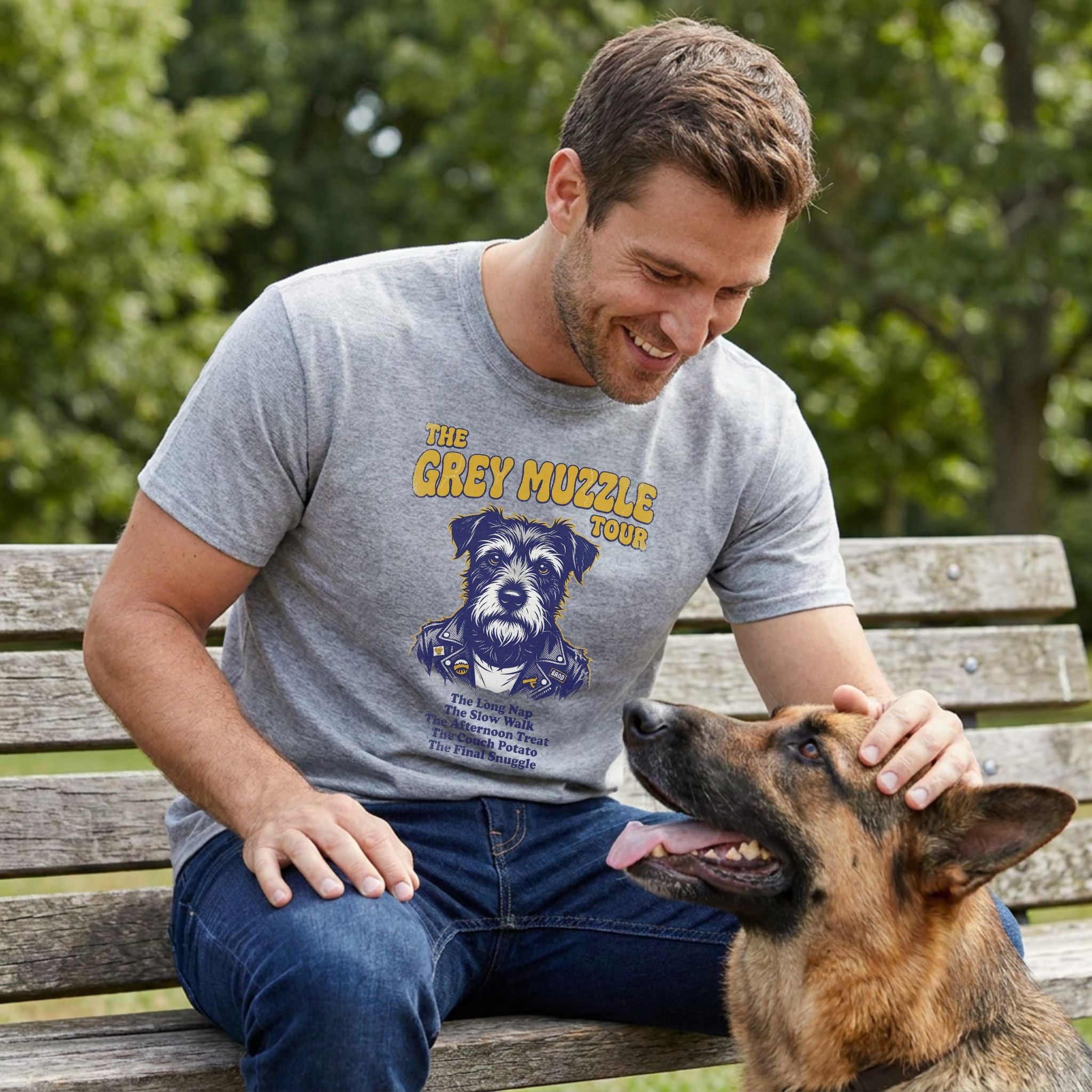Man in a grey "The Grey Muzzle Tour" t-shirt with a dog graphic, petting a German Shepherd on a park bench.