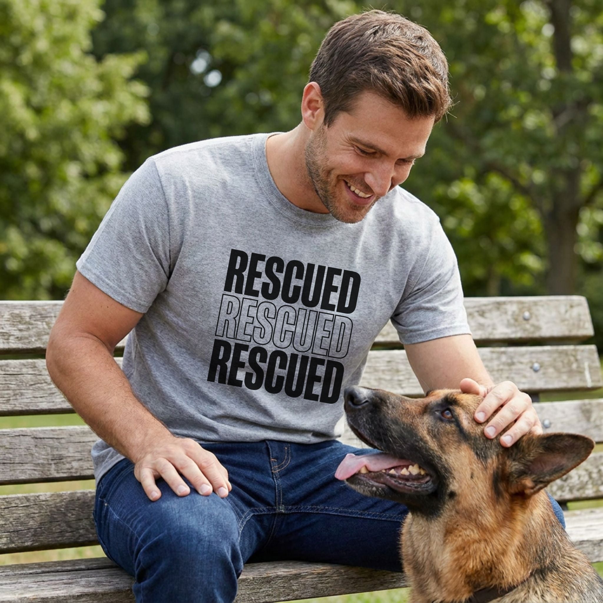 Man in a grey "RESCUED" t-shirt petting a German Shepherd on a park bench.