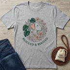 Light grey Gildan Softstyle® t-shirt with "Rescued & Rooted" text and a dog surrounded by plants design.
