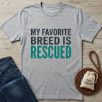 Gray Gildan Softstyle® t-shirt with "My Favorite Breed Is Rescued" text, next to jeans and dog treats.