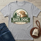 Gray cotton Soul Dog Society T-shirt with a brown dog, trees, and moon logo, next to jeans and dog treats.