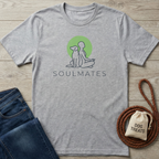 Gray t-shirt with 'Soulmates' design on a wooden surface with jeans and dog treats bag.