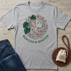 Heather grey cotton t-shirt with a "Rescued & Rooted" graphic featuring a dog, monstera leaves, and pink flowers.