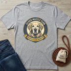 Light grey Silver Muzzle Club t-shirt with a Golden Retriever graphic, next to blue jeans and dog treats.