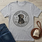 Heather grey "Trust Issues Society" t-shirt with a black dog graphic, next to jeans and dog treats.