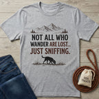 Gray crewneck t-shirt with "NOT ALL WHO WANDER ARE LOST... JUST SNIFFING." text, mountains, and a sniffing dog graphic.