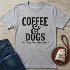 Light grey Gildan Softstyle® t-shirt with "Coffee & Dogs The Only Two Essentials" text, beside jeans and dog treats.